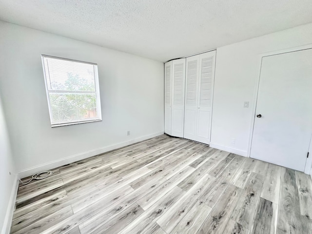 unfurnished bedroom with a closet, a textured ceiling, and light hardwood / wood-style floors