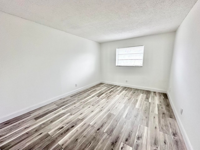 unfurnished room featuring light hardwood / wood-style floors and a textured ceiling