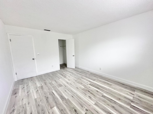 unfurnished room featuring light hardwood / wood-style flooring and a textured ceiling