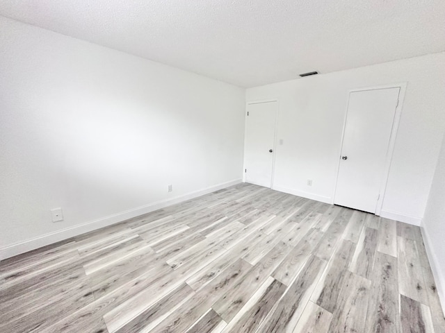 unfurnished room with light hardwood / wood-style floors and a textured ceiling