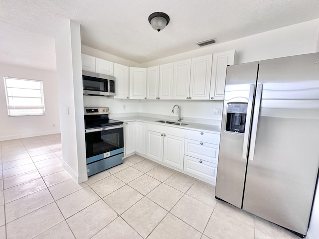 kitchen with white cabinets, sink, light tile flooring, and stainless steel appliances