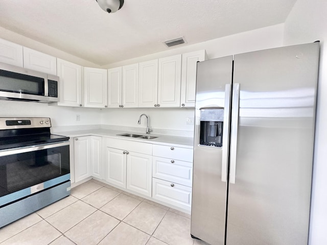 kitchen featuring white cabinets, sink, stainless steel appliances, and light tile flooring