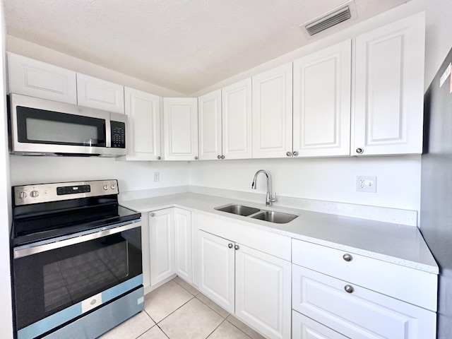 kitchen with light tile floors, stainless steel appliances, white cabinetry, and sink