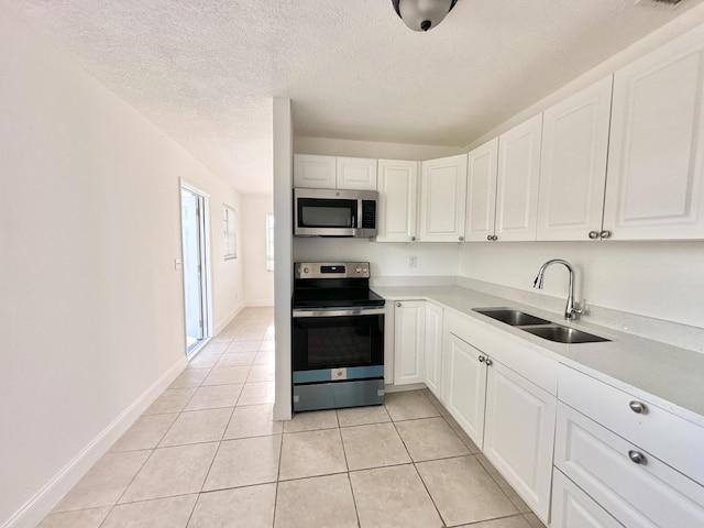 kitchen featuring appliances with stainless steel finishes, a textured ceiling, sink, light tile flooring, and white cabinetry