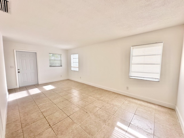 tiled spare room featuring a textured ceiling