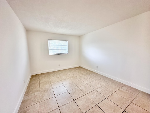 tiled empty room featuring a textured ceiling