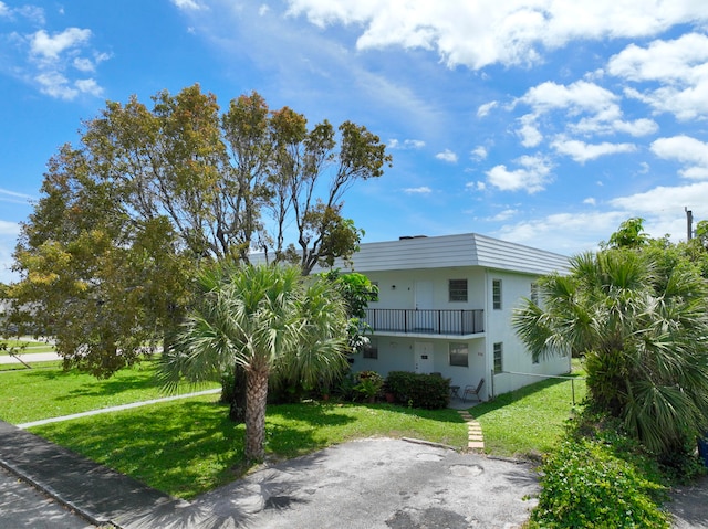 view of side of property with a balcony and a yard