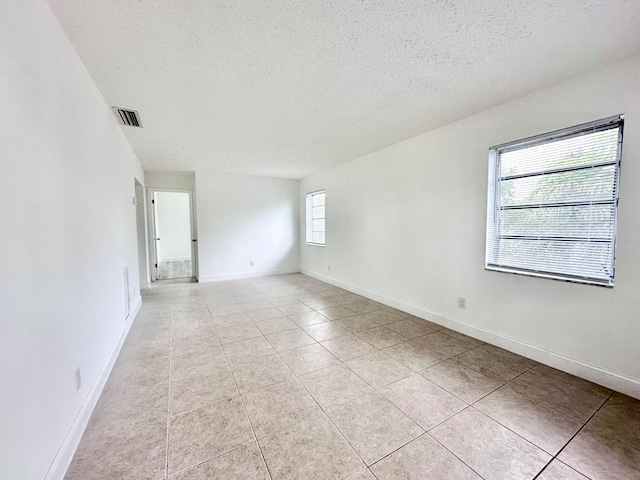 spare room featuring a textured ceiling and light tile flooring