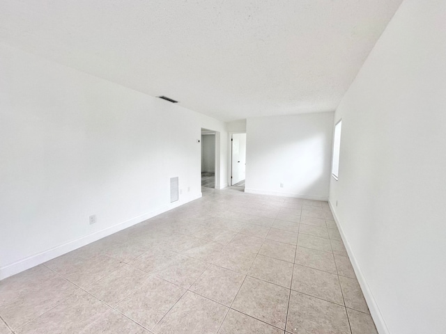 unfurnished room with light tile floors and a textured ceiling