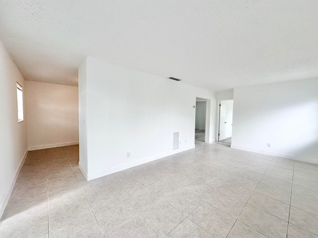 tiled spare room with a textured ceiling