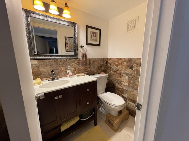 bathroom featuring tile patterned floors, vanity, toilet, and tile walls