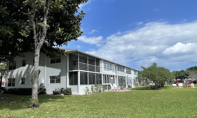 back of property with a lawn and a sunroom