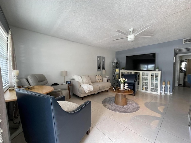 tiled living room featuring ceiling fan, a healthy amount of sunlight, and a textured ceiling