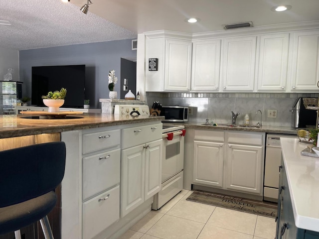 kitchen with dishwasher, white cabinets, light tile patterned floors, and sink