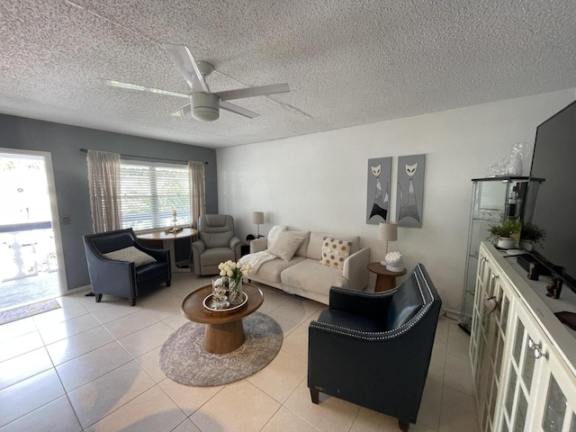 living room featuring ceiling fan, light tile patterned flooring, and a textured ceiling