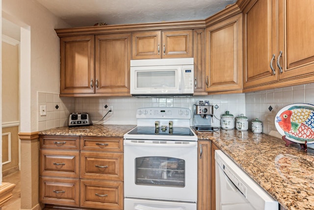 kitchen with white appliances, backsplash, and light stone counters