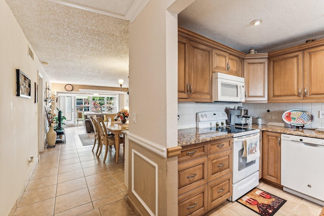 kitchen featuring backsplash, light tile floors, light stone countertops, white appliances, and a textured ceiling