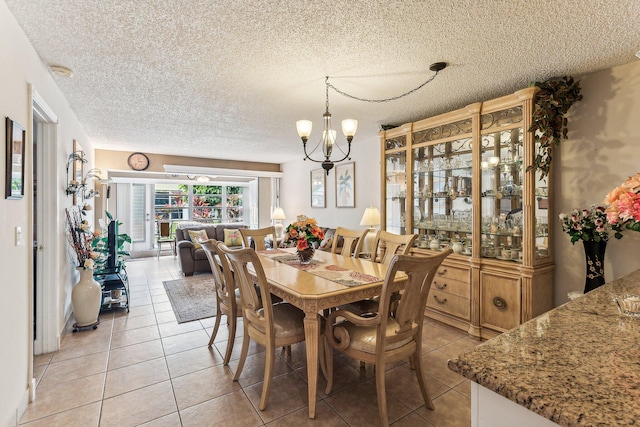 dining area featuring tile floors, a textured ceiling, and an inviting chandelier