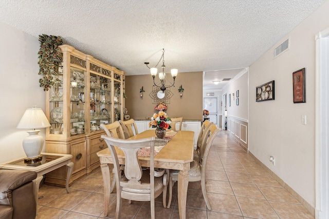 tiled dining space with an inviting chandelier and a textured ceiling