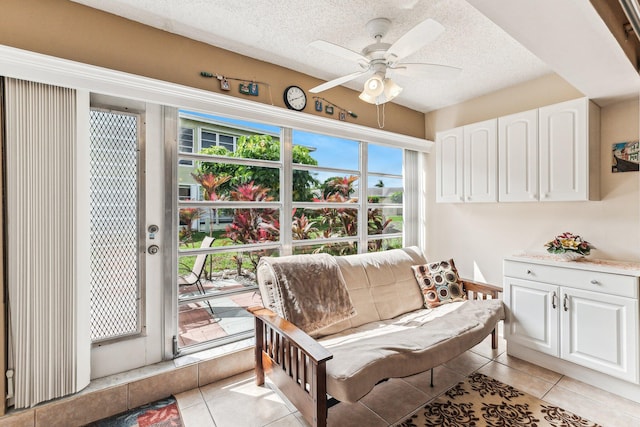 sitting room with ceiling fan, a textured ceiling, and light tile flooring