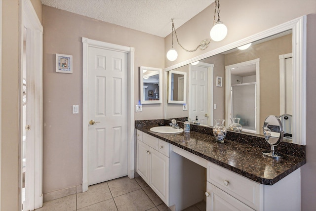 bathroom featuring vanity with extensive cabinet space, a textured ceiling, and tile floors