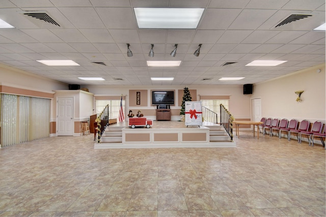 interior space with a paneled ceiling, tile floors, and rail lighting