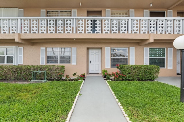 property entrance featuring a lawn and a balcony