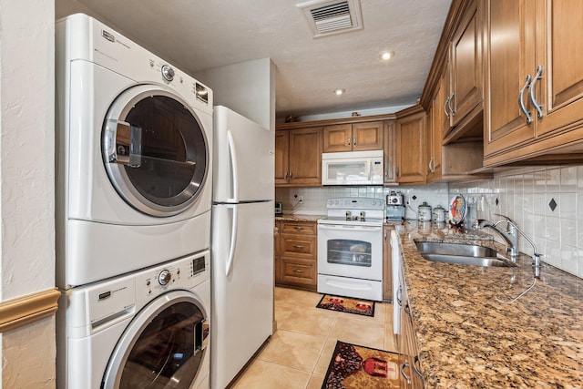 interior space with stacked washer / dryer, sink, and light tile floors