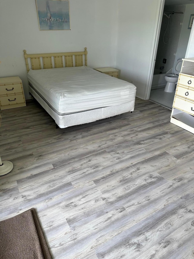 bedroom featuring wood finished floors and ensuite bathroom