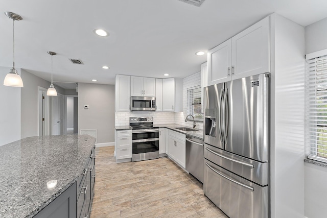 kitchen featuring white cabinetry, sink, stainless steel appliances, and light stone counters