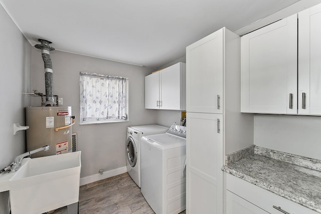 washroom with sink, cabinets, gas water heater, independent washer and dryer, and light hardwood / wood-style floors