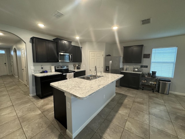 kitchen with a center island with sink, stainless steel appliances, sink, and light tile floors