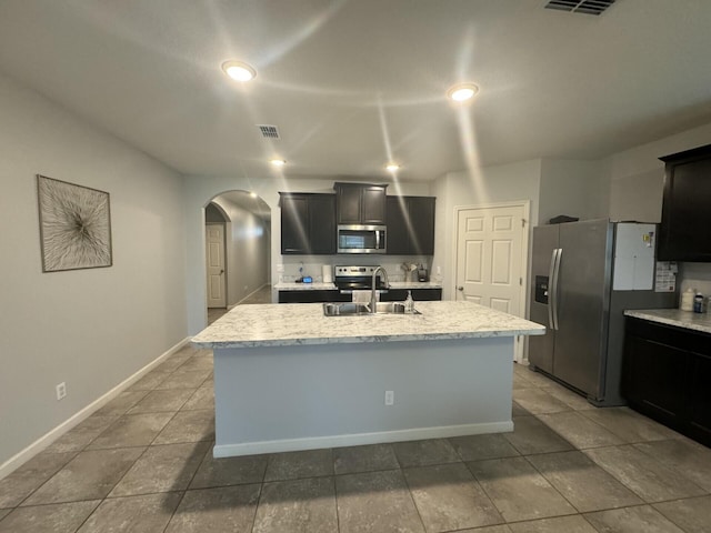 kitchen featuring light stone countertops, tile floors, sink, an island with sink, and stainless steel appliances