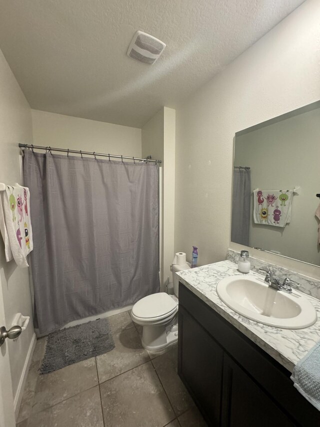 bathroom featuring a textured ceiling, tile floors, vanity with extensive cabinet space, and toilet