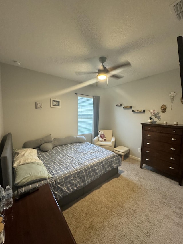 bedroom with a textured ceiling, ceiling fan, and light colored carpet