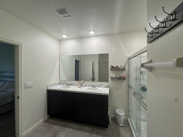 bathroom with an enclosed shower, tile flooring, a textured ceiling, and double vanity