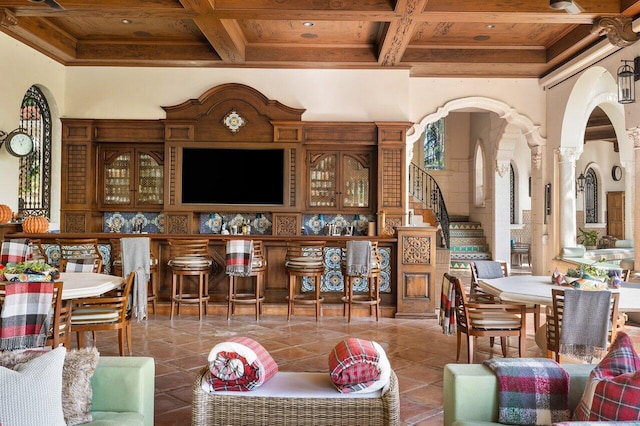 tiled living room with coffered ceiling, decorative columns, beamed ceiling, wood ceiling, and crown molding