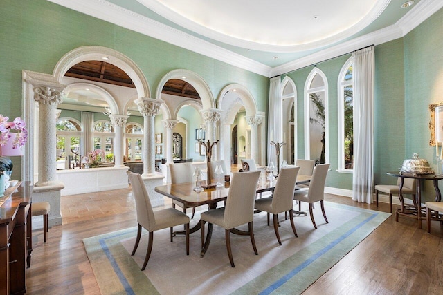 dining room featuring hardwood / wood-style floors, ornamental molding, and decorative columns