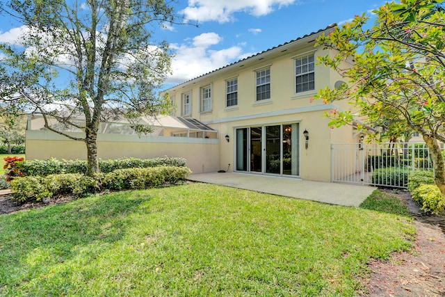 rear view of house with a lawn and a patio