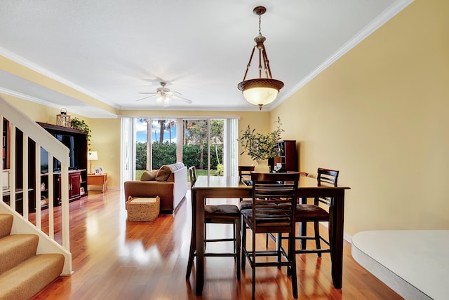 dining space with ornamental molding, wood-type flooring, and ceiling fan