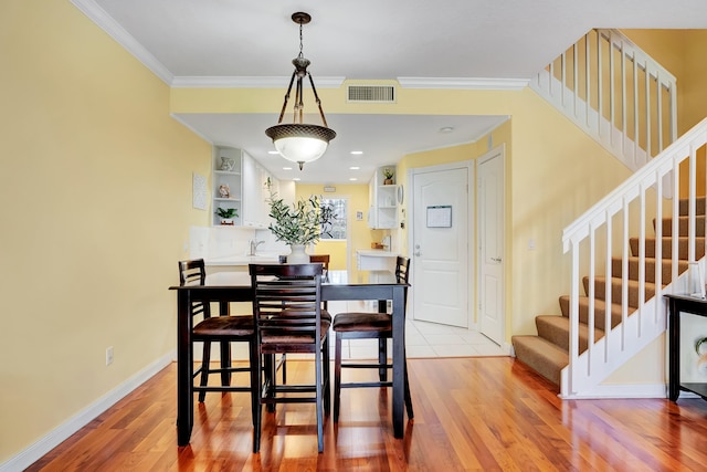 dining room with ornamental molding and light wood-type flooring