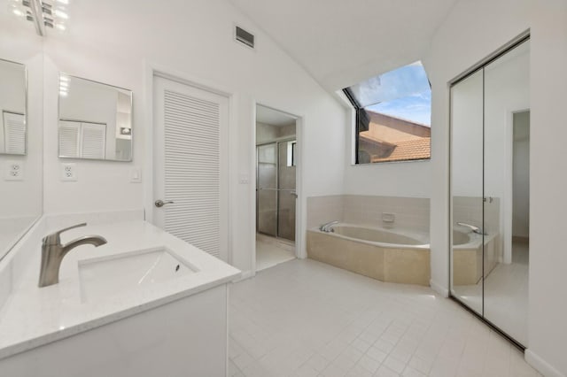 bathroom with independent shower and bath, lofted ceiling with skylight, vanity, and tile flooring