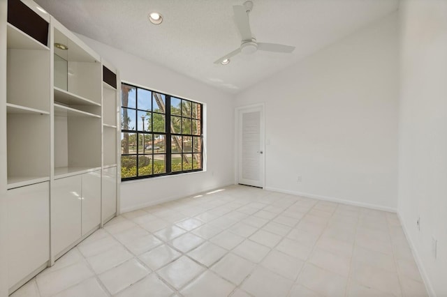 tiled empty room with vaulted ceiling, ceiling fan, and a textured ceiling