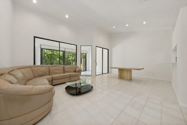 living room featuring a textured ceiling, a towering ceiling, and light tile flooring