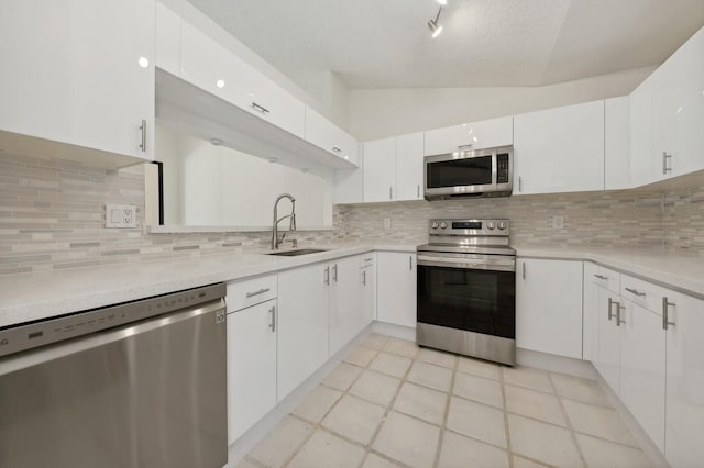 kitchen featuring appliances with stainless steel finishes, light tile floors, white cabinets, sink, and tasteful backsplash