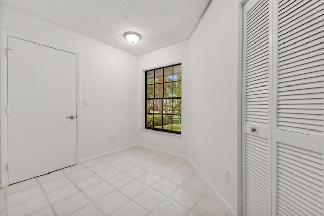 tiled empty room with a textured ceiling