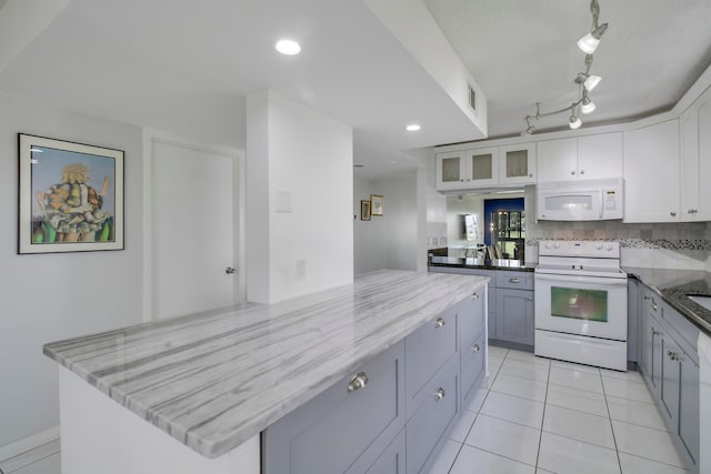 kitchen featuring gray cabinetry, white appliances, white cabinets, light stone countertops, and a kitchen island