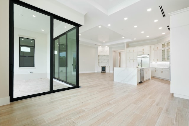 kitchen featuring light stone counters, stainless steel appliances, a tray ceiling, white cabinetry, and a fireplace