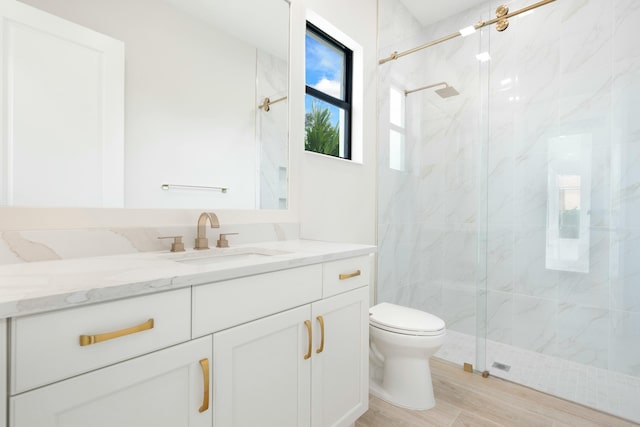 bathroom with hardwood / wood-style floors, a shower with shower door, vanity, and toilet