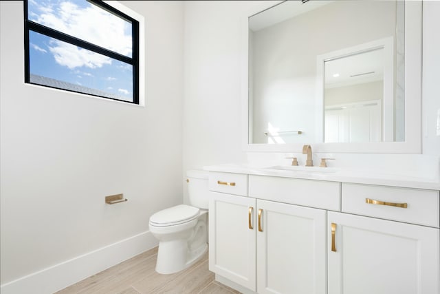 bathroom with toilet, vanity, and hardwood / wood-style flooring